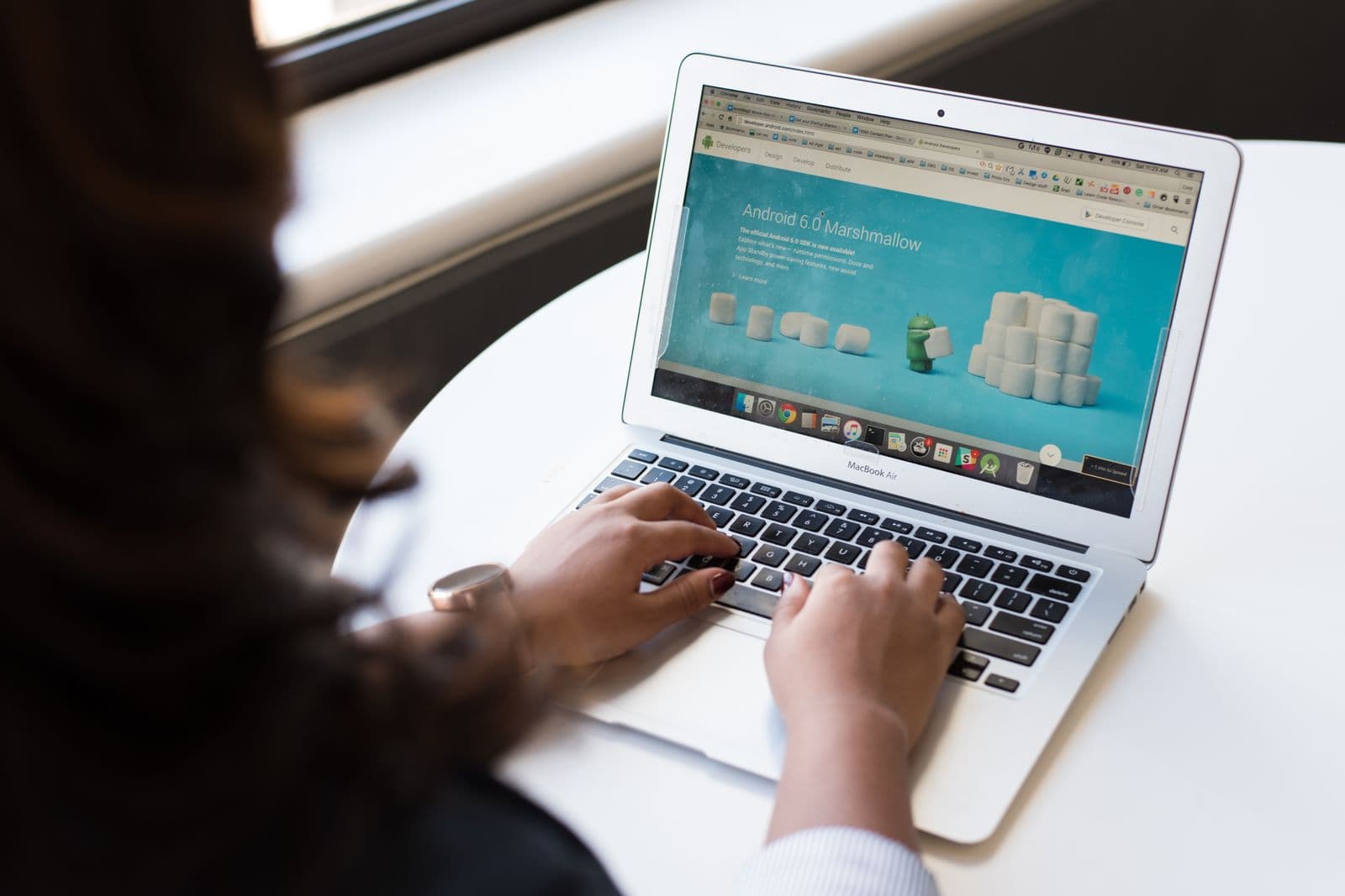 Person typing on a laptop displaying a turquoise webpage on a desk.